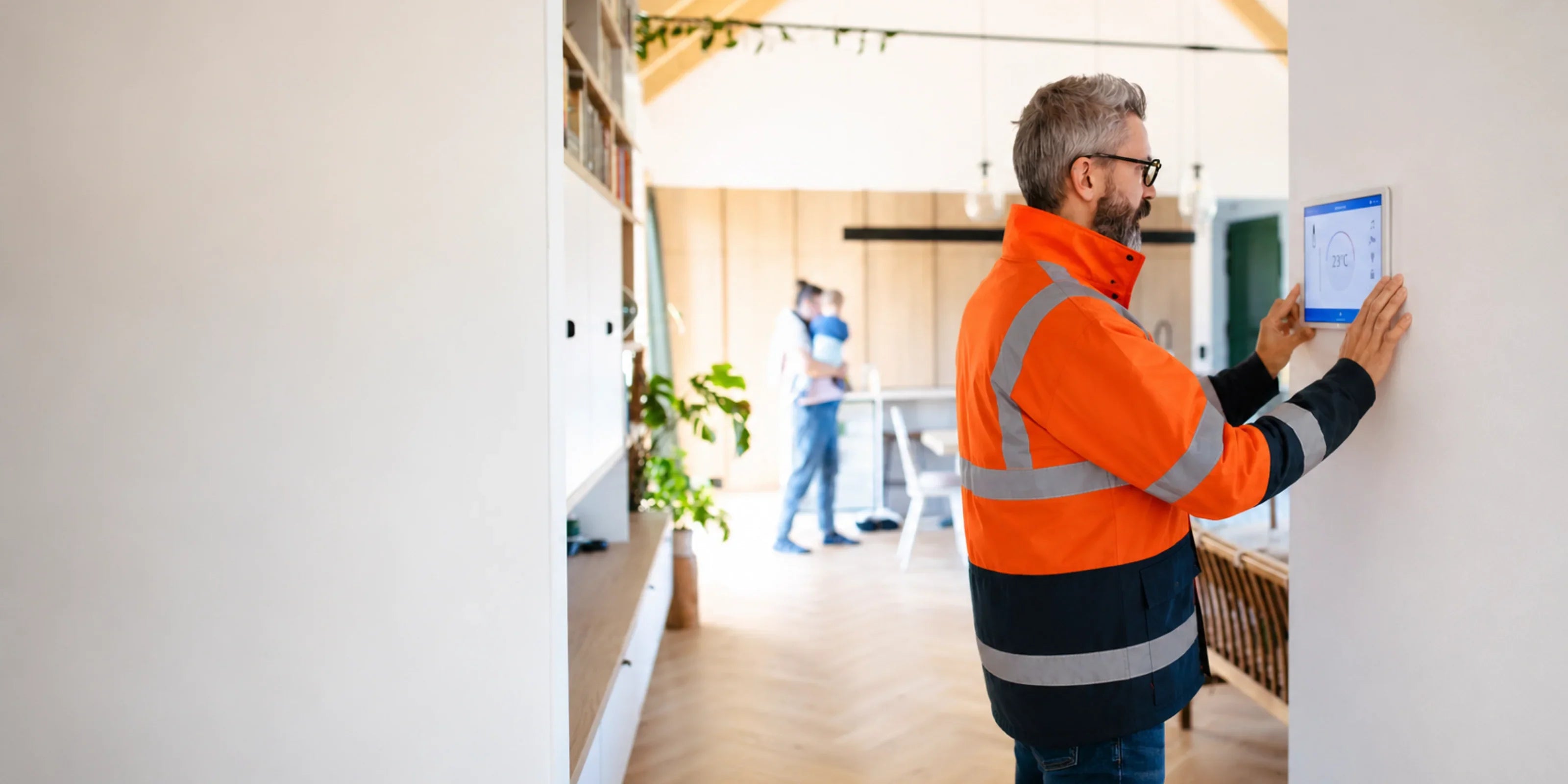 Technician installing smart thermostat in modern home, adjusting temperature settings on digital display